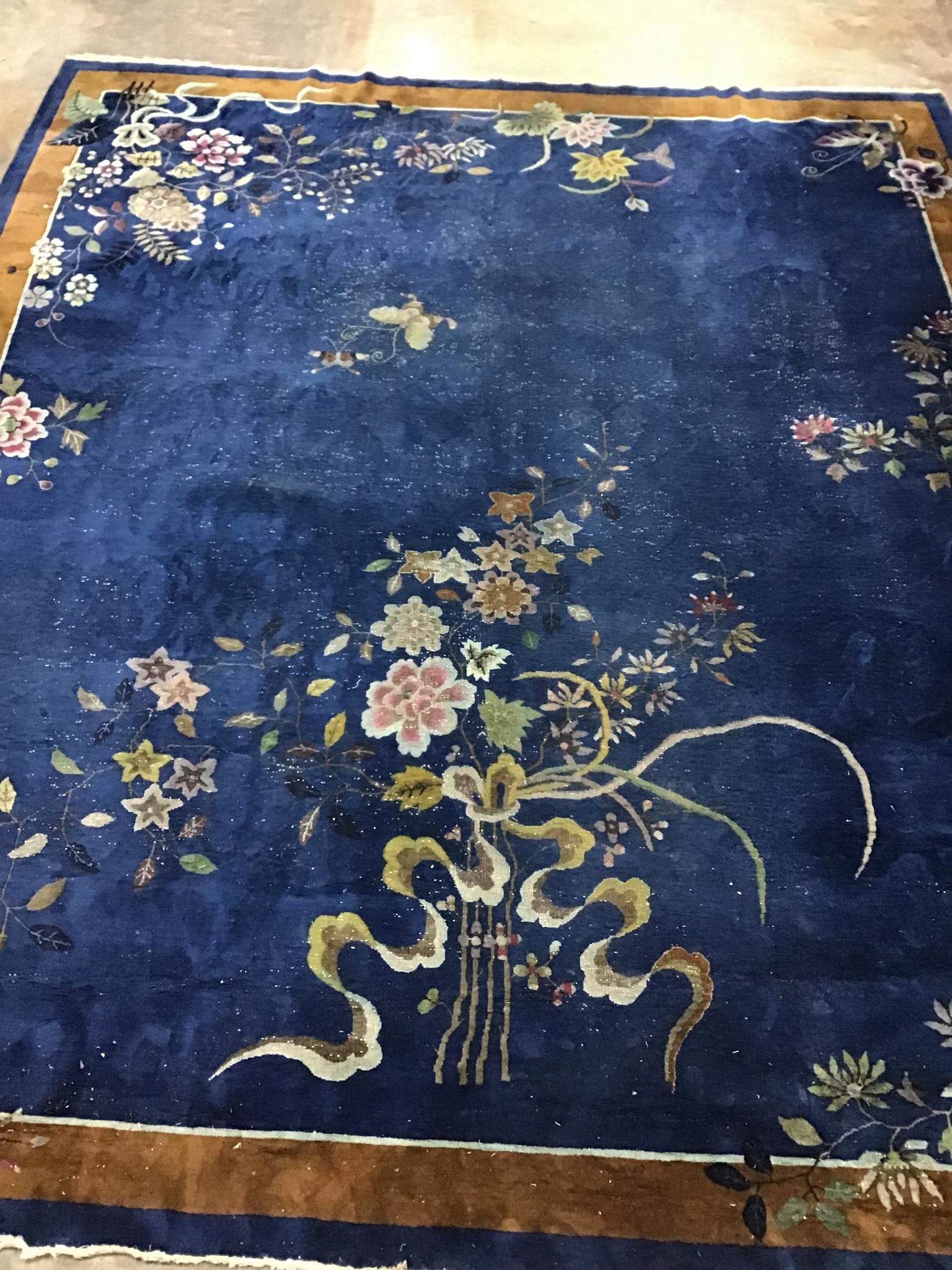 An early 20th century Chinese blue ground carpet woven with butterflies and flowering branches 450cm x 370cm